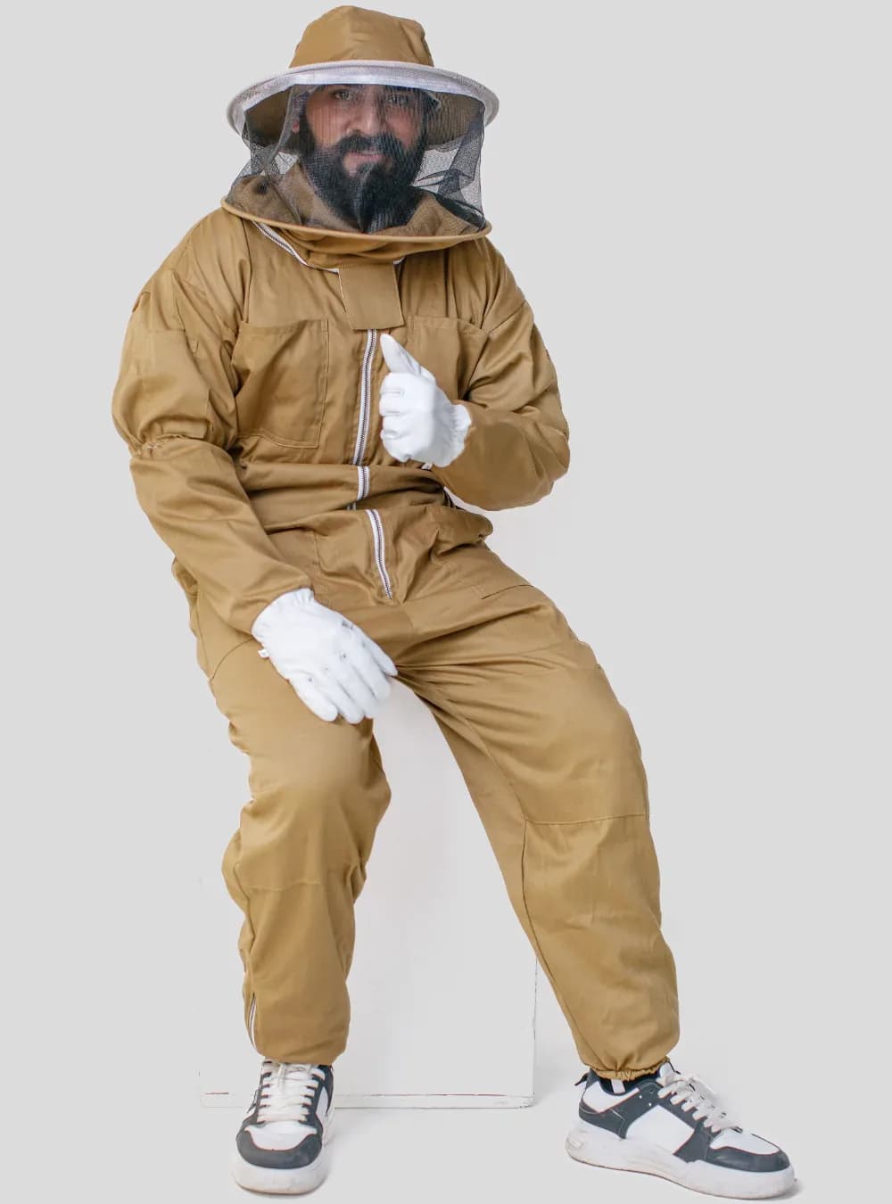 How should a bee suit fit: beekeeper seated in a brown cotton bee suit with room at the seat and knees