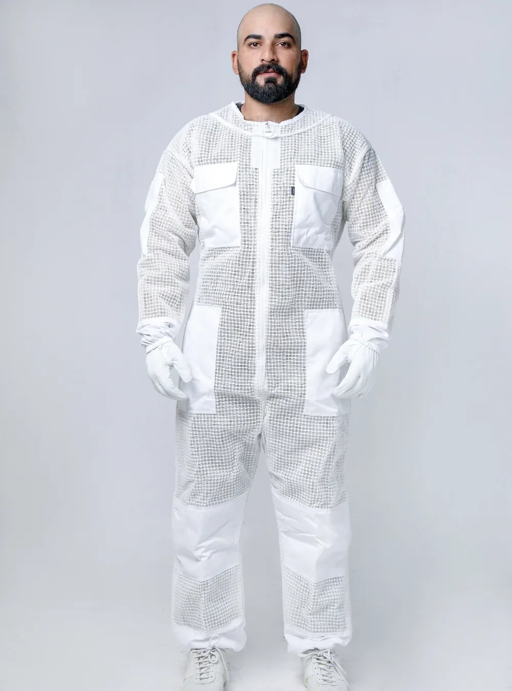 Front view of a beekeeper in a white ventilated suit with the veil folded back, showing room across the chest
